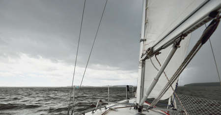 White yacht sailing during the storm. View of the mast, sails, rigging equipment. 32 feet swedish built cruising sailboat. MÃ¤laren lake, Sweden. Summer vacations, recreation, sport, leisure activityの写真素材