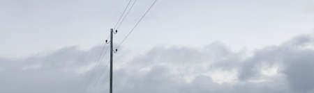 Transformer pole of the country electricity line against dramatic sunset sky with colorful cumulus clouds. Nature, ecology, environmental damage, technology, infrastructure, remote placesの写真素材