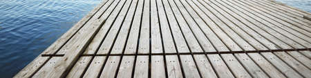 Wooden pier near the river (lake). Clear blue sky, reflections in a still water. Idyllic summer...