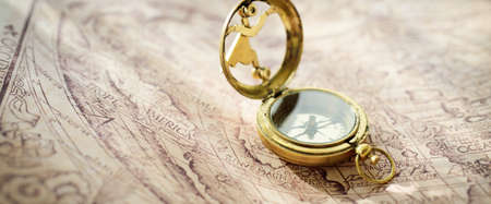 Retro styled golden compass (sundial) and old white nautical chart. Vintage still life. Sailing...