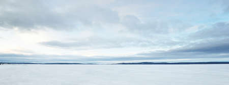 Frozen lake and forest at sunset. Ice texture. Dramatic storm blue sky, cloudscape. Winter wonderland. Nature, ecology, climate change, ecotourism, fickle weather, global warmingの写真素材