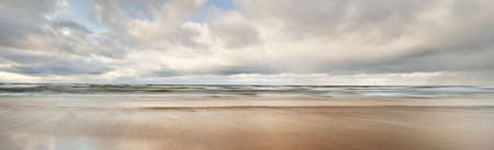 Colorful glowing golden sunset clouds above the Baltic sea. Dramatic sky. Sand, waves and water...