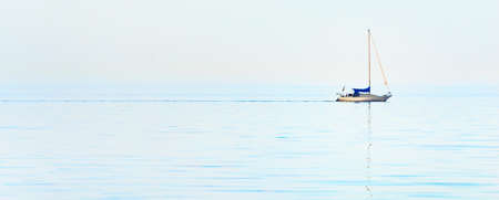 Minimalistic image of a sloop rigged yacht reflecting in a still water. Flat simple seascape. Baltic...