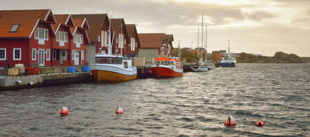 Motorboats, sailing and fishing boats moored to a pier in a small village in Rogaland region,...