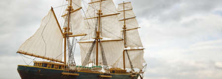 Antiquarian wooden scale model of the clipper tall ship, close-up. Dramatic sky in the background....