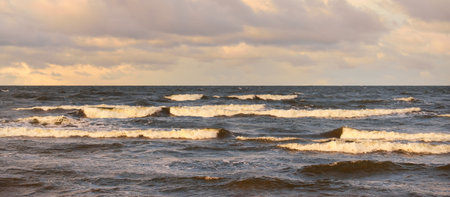 Dark storm sky above the Baltic sea, waves and water splashes. Dramatic cloudscape. Nature, environment, fickle weather, climate change. Atmospheric scenery. Panoramic viewの写真素材