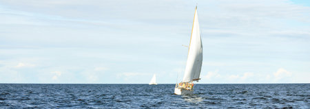Old expensive vintage wooden sailboat (yawl) close-up, sailing in an open sea. Stunning cloudscape....