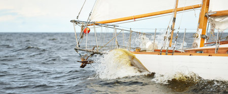 Old expensive vintage wooden sailboat (yawl) close-up, sailing in an open sea. Dramatic cloudscape....