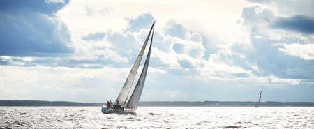 Sailing yacht regatta. Modern sailboat racing through the waves. Dramatic sky before the...