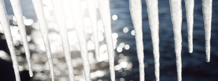 Large icicles close-up. Clear blue sky. Concept winter landscape. Midday sun. Seasons, ecology,...
