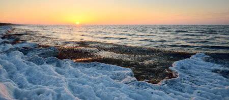 Frozen Baltic sea shore at sunset, snow texture close-up. Clear sky. Picturesque winter scenery....