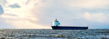 Large cargo ship sailing in the Baltic sea at sunset. Soft golden sunlight. Concept seascape....