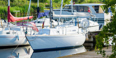 Elegant and modern sailboats moored to a pier in a yacht marina. Vacations, transportation, sport,...