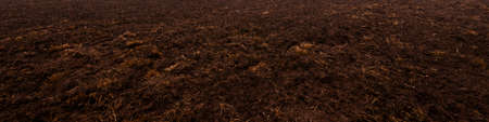 Plowed agricultural field, tractor tracks, soil texture close-up. Rural scene. Panoramic landscape. Farm and food industry, alternative energy and production, environmental conservation themeの写真素材