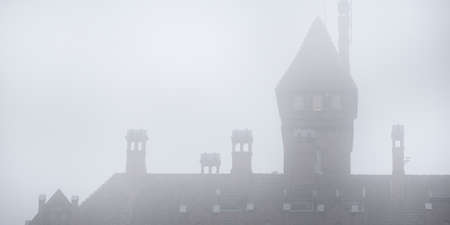 Castle towers in a fog. Jaunmoku pils, Latvia. Dark atmospheric landscape. Panoramic view