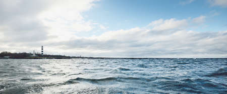 A lighthouse under the dark clouds after the thunderstorm. A view from the sailing boat. Dramatic...