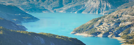 Panoramic view of the mountain lake Lac de serre-poncon in French Alps on a sunny day. Clear blue sky, still water. Travel destinations, tourism, landmark, nature, Christmas vacations in Franceの写真素材
