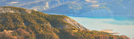 Panoramic view of the mountain lake Lac de serre-poncon in French Alps on a sunny day. Clear blue sky, still water. Travel destinations, tourism, landmark, nature, Christmas vacations in Franceの写真素材