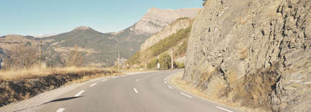 An asphalt road (highway) in France, Alps mountains, Parc Ecrins. Panoramic view from the car. Mountain peaks. Winter vacations, road trip, transportationの写真素材