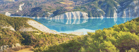 Panoramic view of the mountain lake Lac de serre-poncon in French Alps on a sunny day. Clear blue sky, still water. Travel destinations, tourism, landmark, nature, Christmas vacations in Franceの写真素材