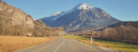 Winding asphalt road (highway) in Parc Ecrins, France. French Alps. Mountain peaks, clear blue sky. Panoramic landscape. Nature, travel destinations, wanderlust conceptsの写真素材
