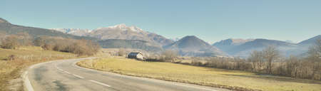 Winding asphalt road (highway) in Parc Ecrins, France. French Alps. Mountain peaks, clear blue sky. Panoramic landscape. Nature, travel destinations, wanderlust conceptsの写真素材