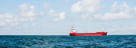 Large cargo ship sailing in the Baltic sea. Concept seascape. Panoramic view from the sailing boat. Freight transportation, nautical vessel, logisticsの写真素材