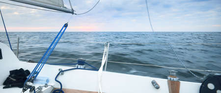 Sailing in the cockpit of a yacht in an open sea at sunset. Dramatic sky with colorful clouds after...