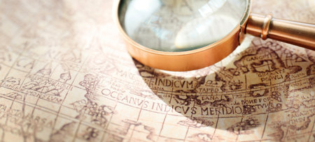 Retro copper colored magnifying glass and old white nautical chart close-up. Vintage still life....