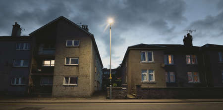 An empty street (asphalt road) between houses and a small harbor at night. People are staying home...