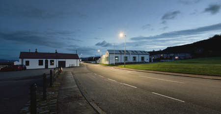 An empty street (asphalt road) between houses and a small harbor at night. People are staying home because of COVID-19 outbreak. Ardrishaig, Crinan canal, Scotland, UK. Quarantine, lockdown conceptsの写真素材