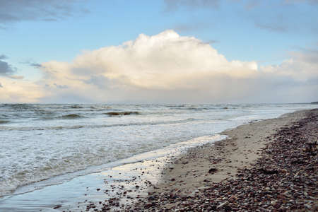 Baltic sea shore at sunset. Beach, sand dunes. Dramatic sky flowing clouds. Soft sunlight. Nature, weather, environment, eco tourismの写真素材