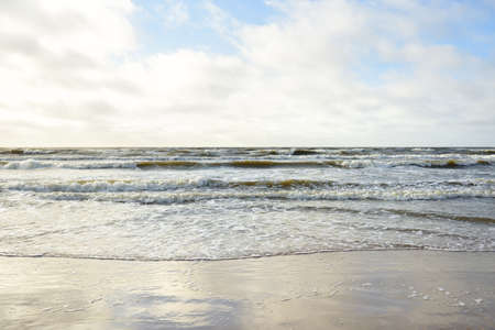 Panoramic view of Baltic sea from sandy shore (sand dunes). Dramatic sky with glowing clouds. Waves, water splashes. Idyllic seascape. Spring weather, climate change, natureの写真素材