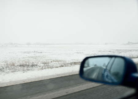 Empty highway (asphalt road) through the snow-covered forest and fields, rural area. View from the car. Europe. Nature, christmas vacations, remote places, winter tires, dangerous driving conceptの写真素材