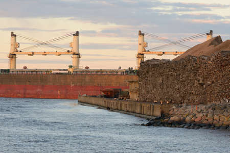 Large cargo ship arriving in port at sunset. Baltic sea.  Freight transportation, nautical vessel,...