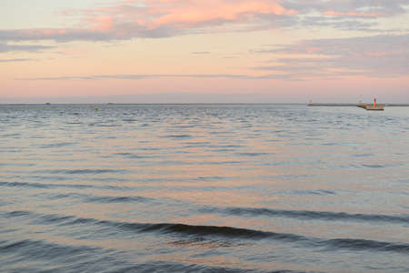 Baltic sea at sunset. Dramatic sky, blue and pink glowing clouds, golden sunlight. Waves, splashing water. Picturesque scenery, seascape, nature. Panoramic viewの写真素材