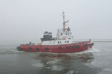 Tug boat in a thick fog. Baltic sea. Winter seascape. Freight transportation, nautical vessel,...