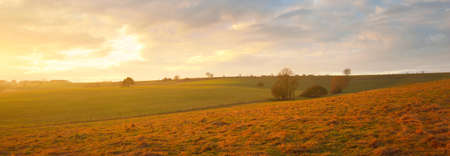 Picturesque panoramic scenery of the plowed agricultural field. Dramatic sky with glowing clouds, soft sunlight. France, Europe. Autumn, seasons, warm winter, climate change, tourism, farm industryの写真素材