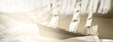 Retro golden compass (sundial), wooden tall ship scale model, old nautical chart close-up. Vintage still life. Sailing, travel, collecting, hobby, souvenir, gift, toy for kids. Playroom interior decorの写真素材