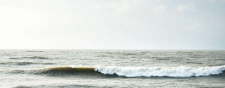 Baltic sea shore (sand dunes) at sunset. Soft sunlight, dramatic sky, waves and water splashes. Idyllic seascape. Latvia, Europe. Spring, weather, climate change, nature. Panorama, copy spaceの写真素材