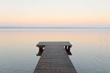 Forest lake (river) at sunrise. Wooden pier (boardwalk). Soft sunlight, mist, reflections on water....