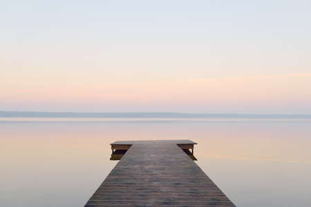 Forest lake (river) at sunrise. Wooden pier (boardwalk). Soft sunlight, mist, reflections on water. Idyllic autumn landscape. Pure nature, ecotourism, hiking, exploringの写真素材