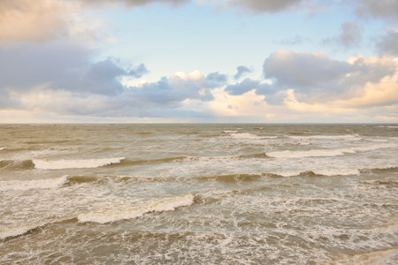 Baltic sea at sunset. Dramatic sky, blue and pink glowing clouds, golden sunlight. Waves, splashing...