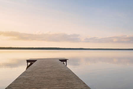 Forest lake (river) at sunset. Wooden pier. Glowing clouds, symmetry reflections in a still crystal clear water. Idyllic landscape. Nature, ecology, ecological reserve, ecotourism, hiking, vacationsの写真素材