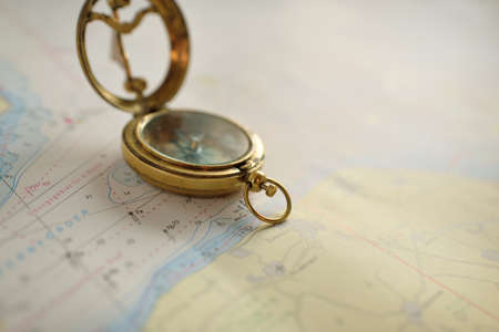 Retro style antique golden compass (sundial) and old nautical chart close-up. Vintage still life....