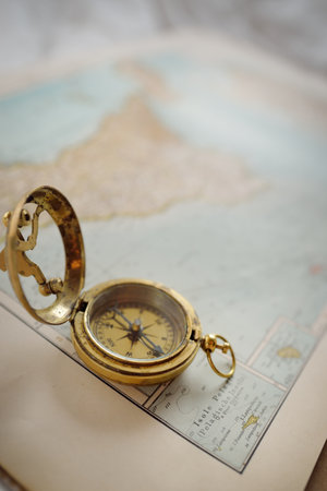 Retro style antique golden compass (sundial) and old nautical chart close-up. Vintage still life....