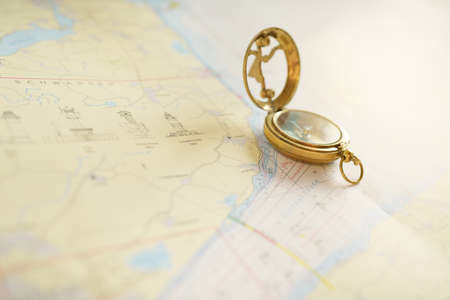 Retro style antique golden compass (sundial) and old nautical chart close-up. Vintage still life. Sailing accessories. Wanderlust, travel and navigation theme. Graphic resources, copy spaceの写真素材