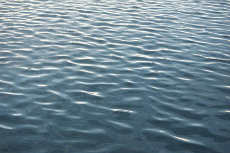 Water surface texture. Soft sunset light, reflections on water. Nature, environment, sea, ocean, river, lake themesの写真素材