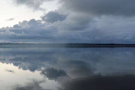 Forest river (lake) at sunset. Dramatic sky, dark glowing clouds. Symmetry reflections in a crystal...