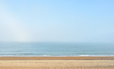 Panoramic view of the Baltic sea shore in a fog at sunrise. Beach, sand dunes. Soft sunlight. Idyllic summer seascape. Nature, environment, vacations, ecotourism, walking and exploring conceptsの写真素材